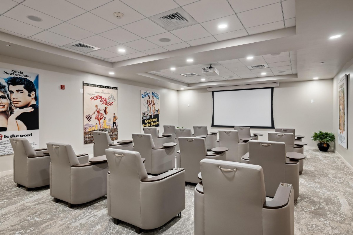 A modern home theater room with comfortable seating and movie posters on the walls.