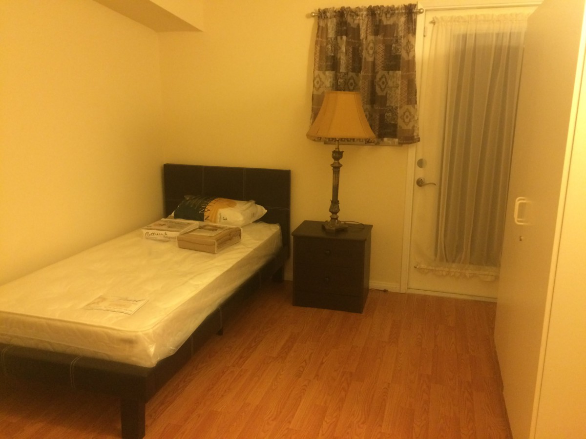 A cozy bedroom with a single bed, nightstand, and lamp.