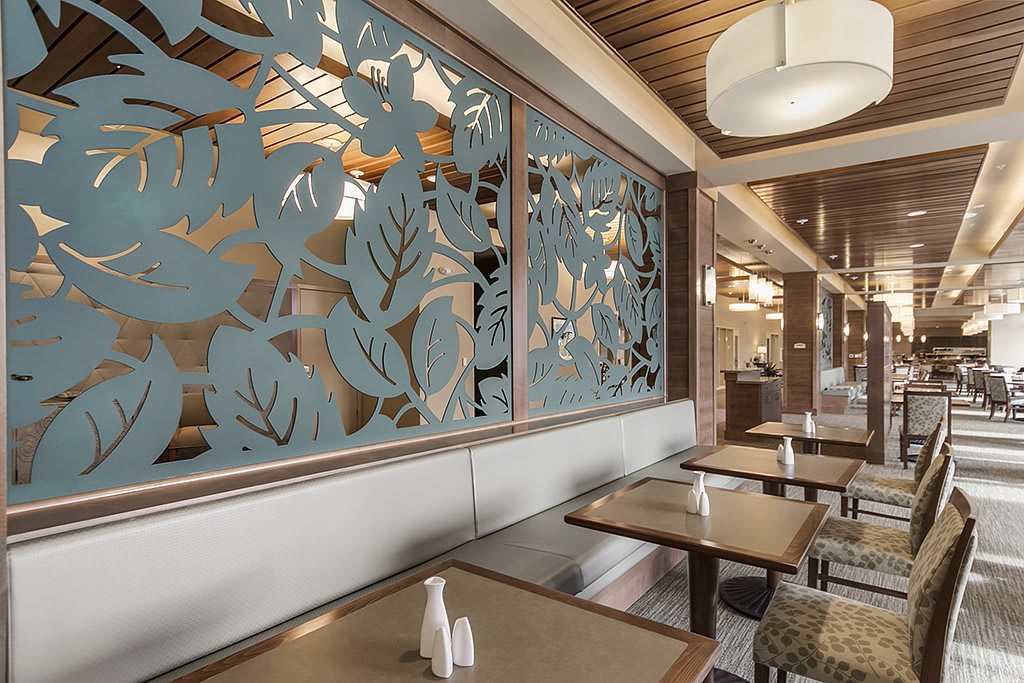 A modern restaurant interior featuring decorative wall panels, wooden elements, and stylish lighting.