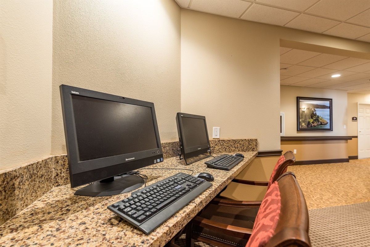 A quiet workspace featuring two desktop computers on a granite countertop.
