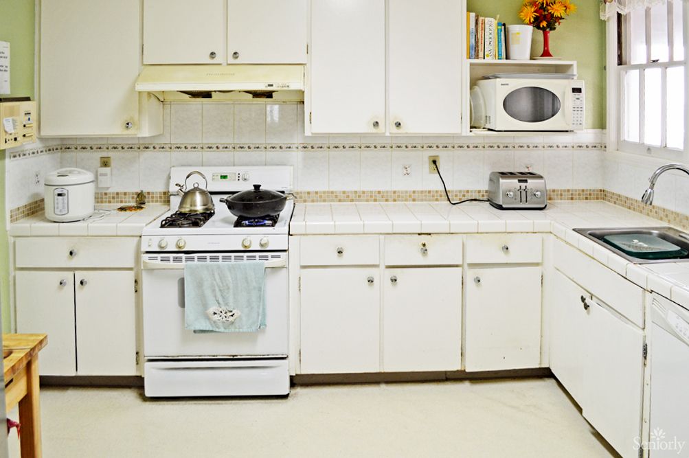 A kitchen featuring white cabinets, a stove, microwave, and toaster on the countertop.