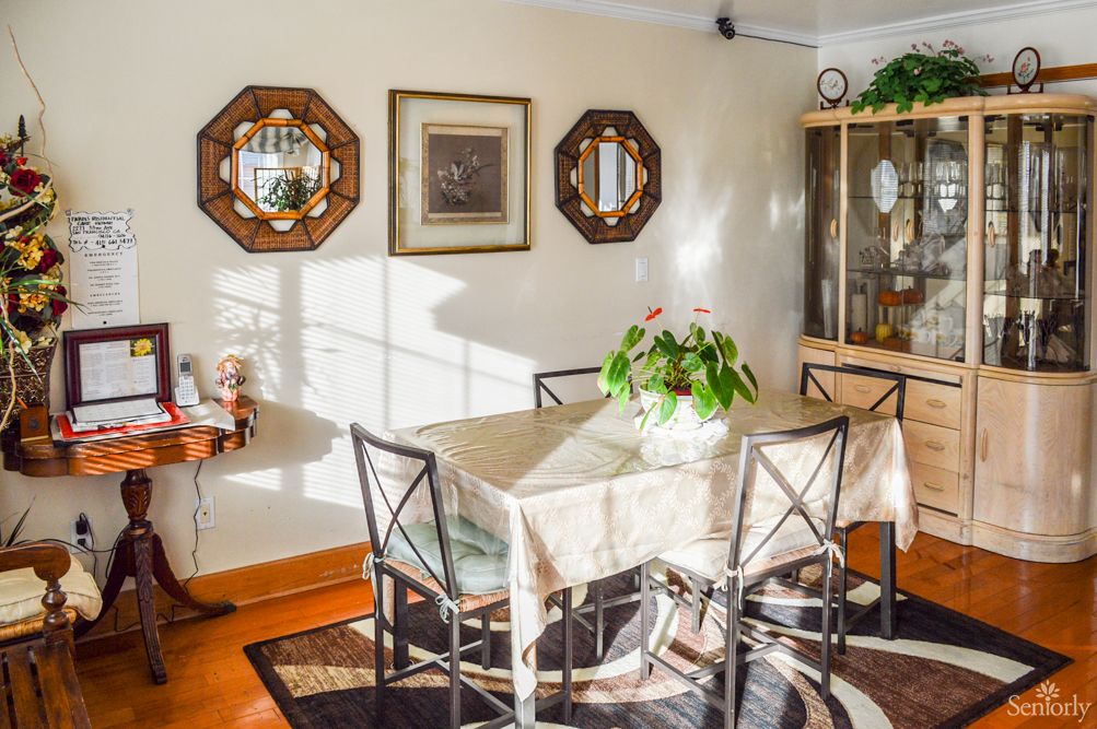 A cozy dining room with a table set for four, adorned with a potted plant and surrounded by elegant decor.
