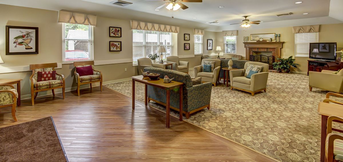 A cozy and well-decorated living room with ample seating, featuring a combination of carpet and wooden flooring.