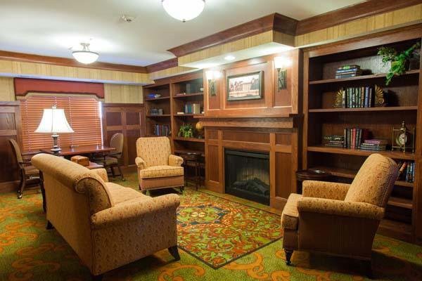 A cozy living room features comfortable armchairs, a fireplace, and built-in bookshelves.