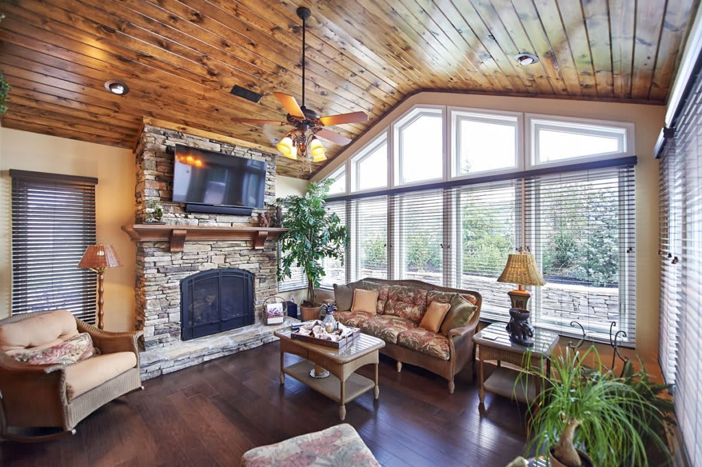 A cozy living room with a stone fireplace and large windows.