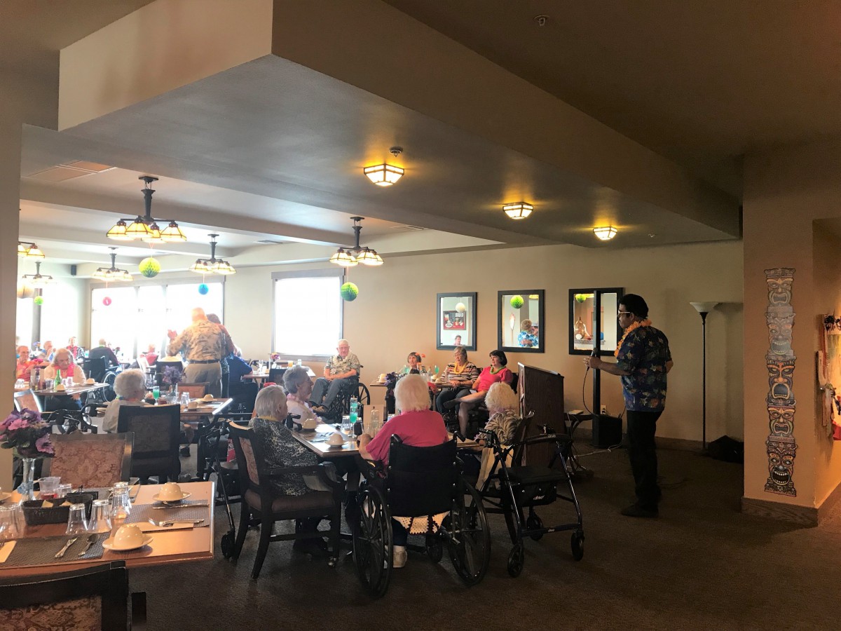 A group of people gathered indoors, some in wheelchairs, socializing at a restaurant.