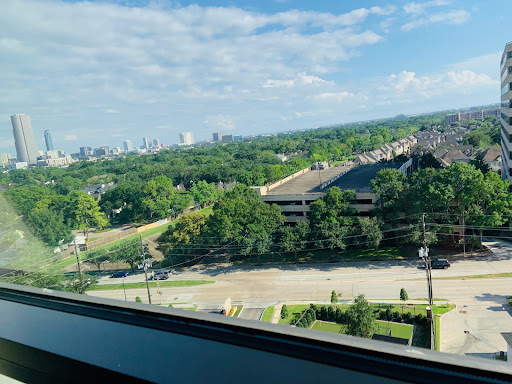 A panoramic view of a city skyline surrounded by greenery under a clear blue sky.
