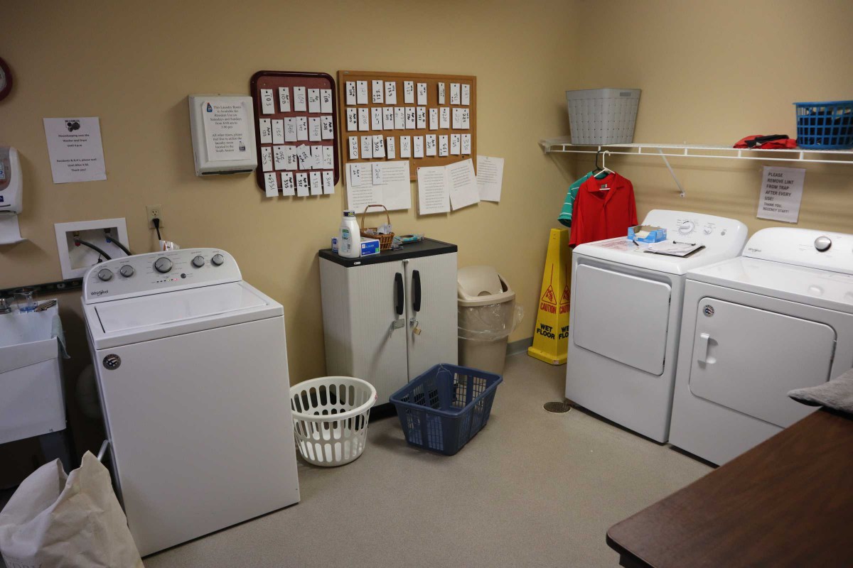 A laundry room with washing machines, a dryer, and cleaning supplies.