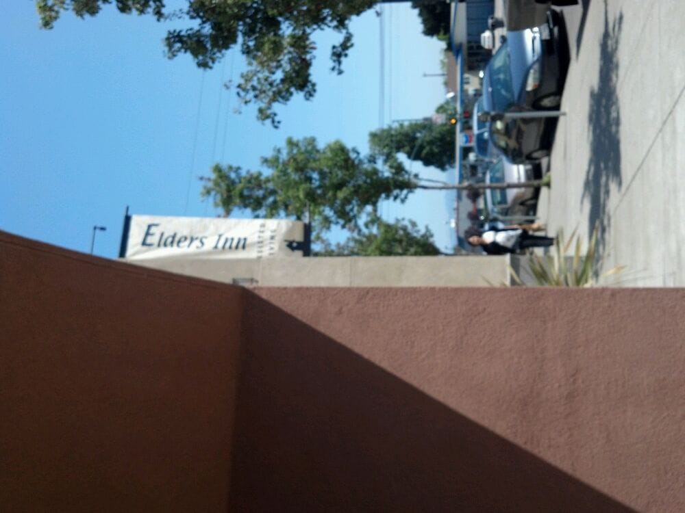 A street view with a building sign and parked cars.