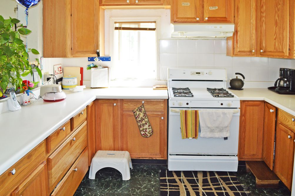 A cozy kitchen with wooden cabinets and a white stove, featuring a window above the counter.