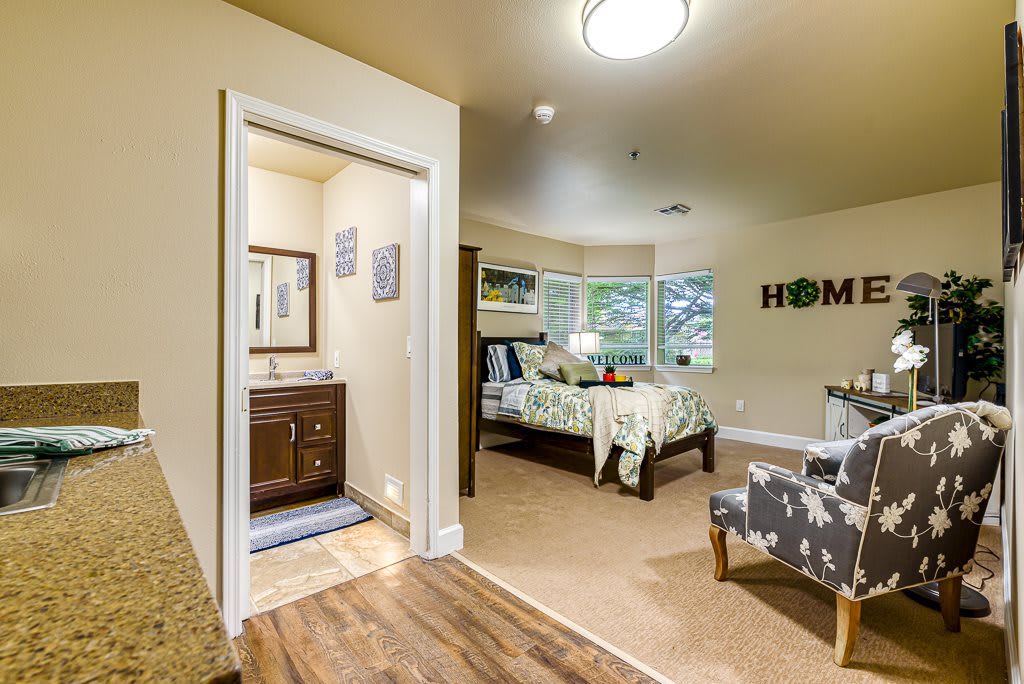 A cozy bedroom with an adjoining bathroom, featuring modern interior design and homey decor.