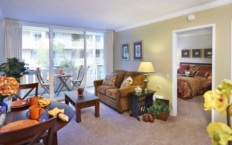A cozy living room with a sofa and coffee table, overlooking a balcony.