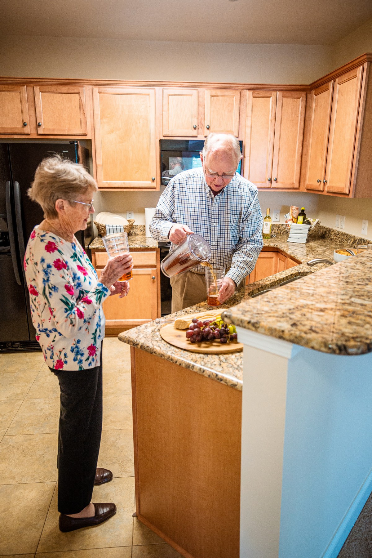 An elderly couple preparing food together in their kitchen.