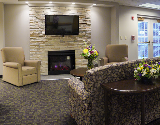 A cozy living room featuring a stone fireplace, comfortable seating, and a television.