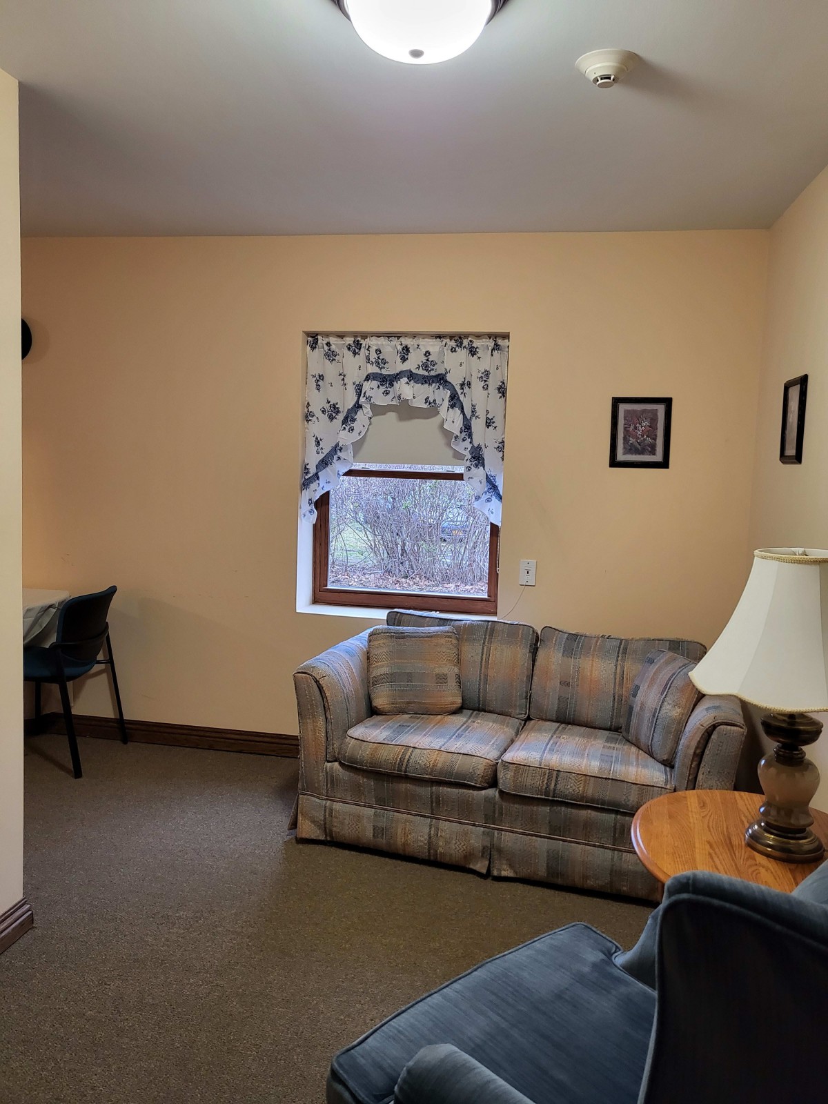 A cozy living room with a couch, desk, and lamp.