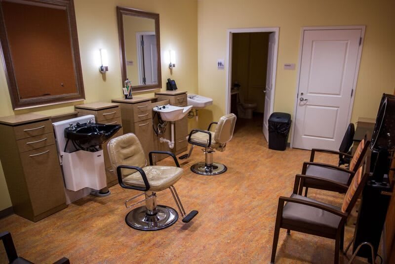 A cozy barbershop interior with styling chairs, mirrors, and a waiting area.