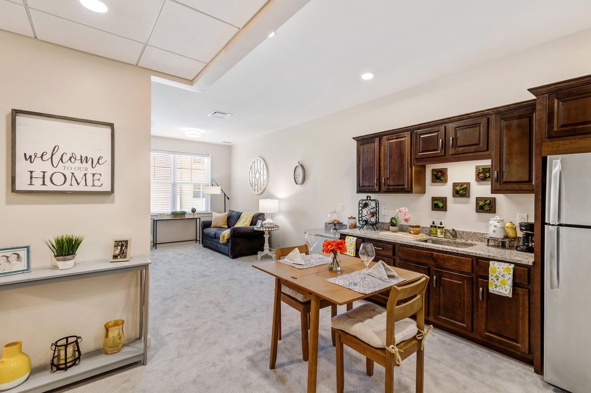 A modern open space featuring a kitchen with wooden cabinets and a cozy dining area leading to the living room.
