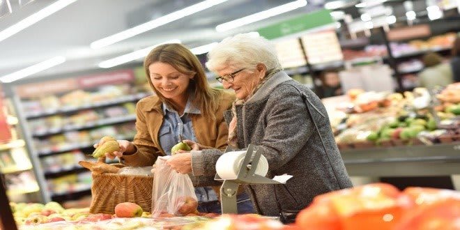 An elderly woman and a young woman shopping for fruits in a supermarket.