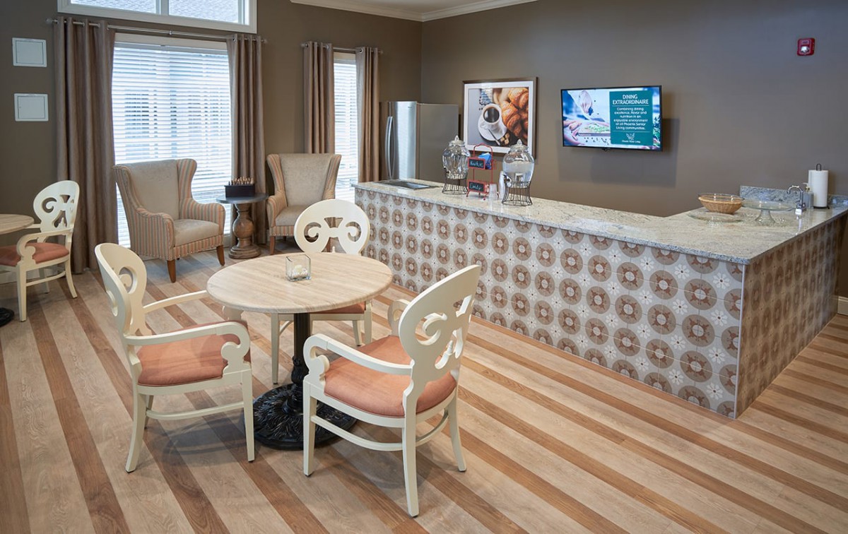 A cozy lobby with a seating area featuring a small table and chairs, alongside a reception desk with decorative wallpaper.