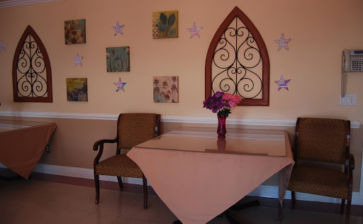 A cozy corner featuring a wooden table and chair adorned with flowers, complemented by decorative wall art.