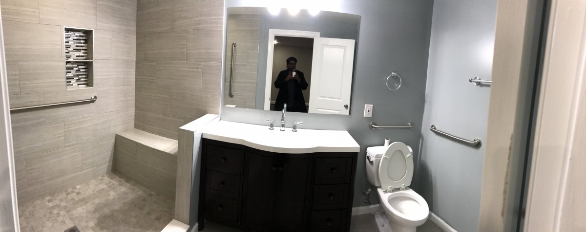 A modern bathroom with a large mirror above the sink and a toilet next to it.