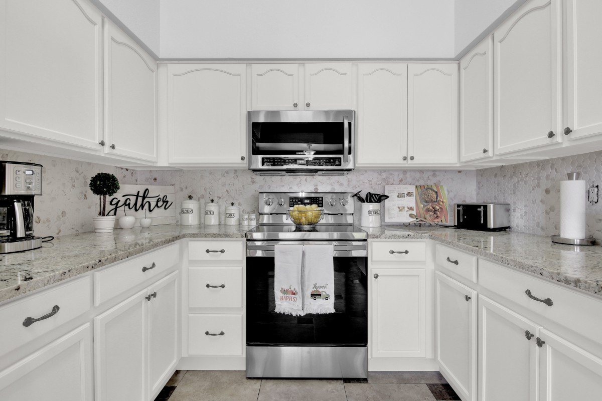 A modern kitchen with white cabinets and stainless steel appliances.