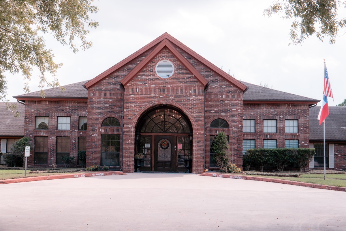 A large brick building with a central arched entrance and symmetrical windows.