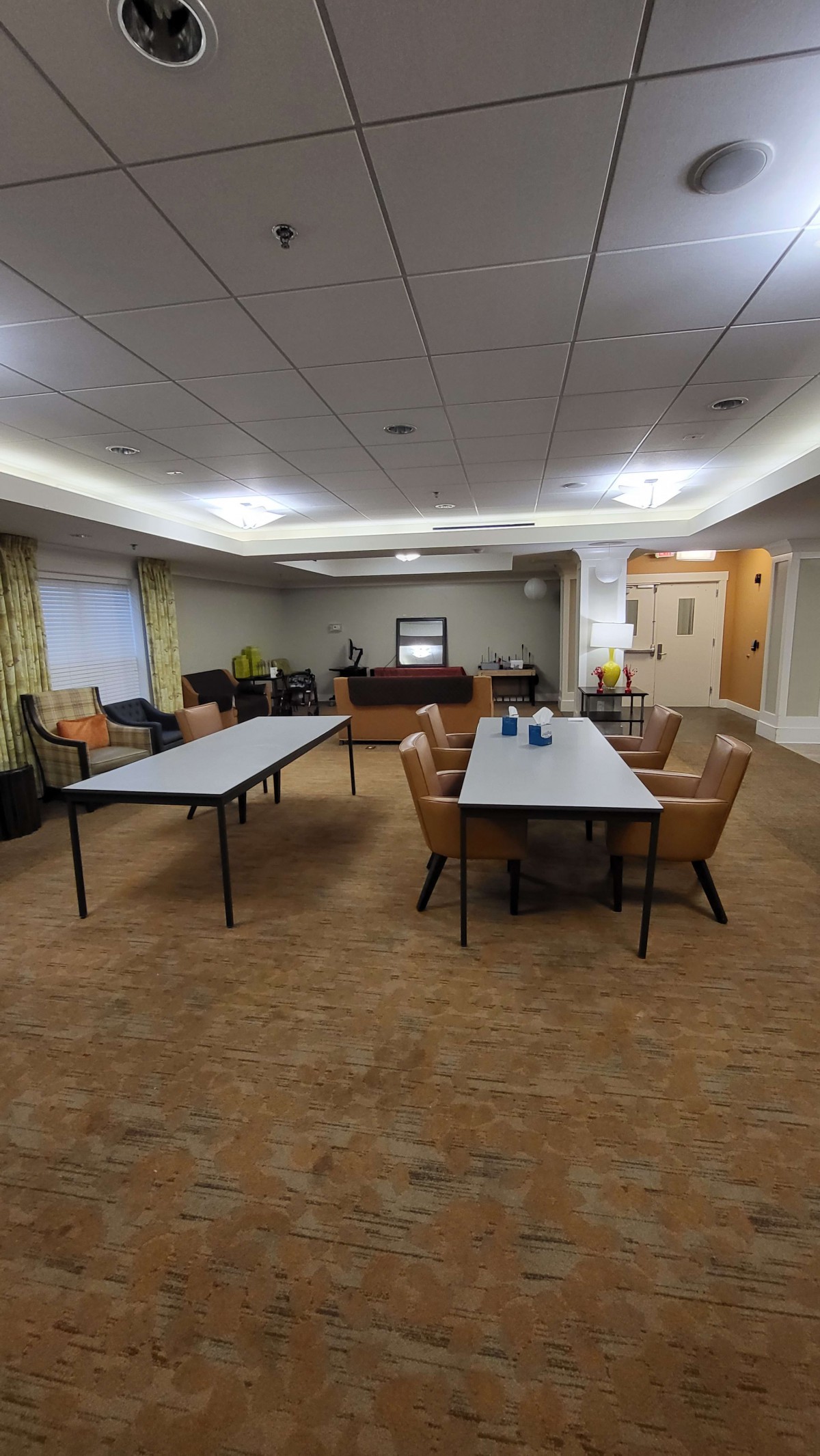 A spacious conference room with tables and chairs, prepared for a meeting.