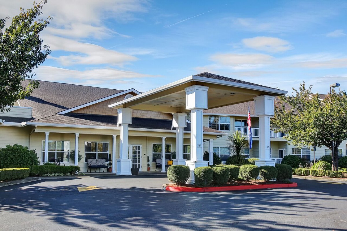 A hotel entrance with a covered driveway and landscaped surroundings.