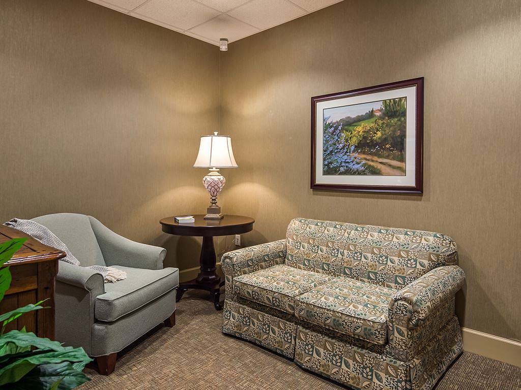 A cozy waiting room with a sofa, armchair, and lamp.