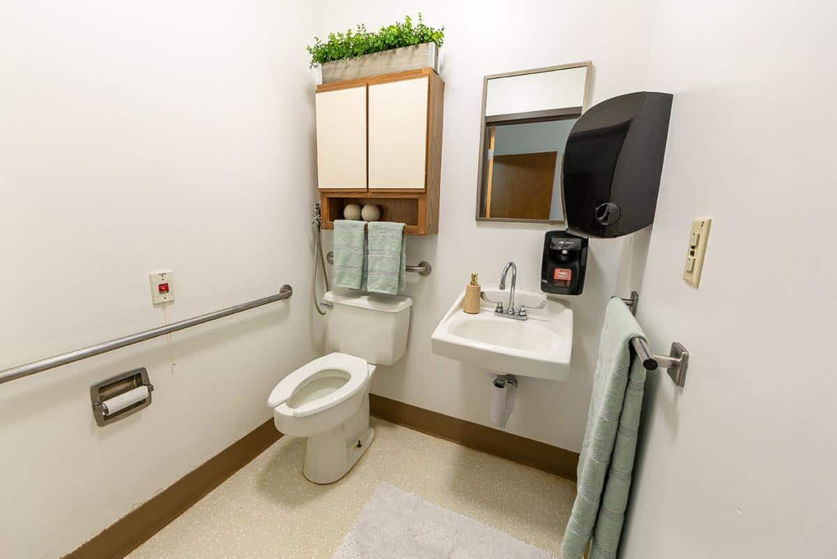 A neatly organized bathroom with a toilet, sink, mirror, and towel rack.