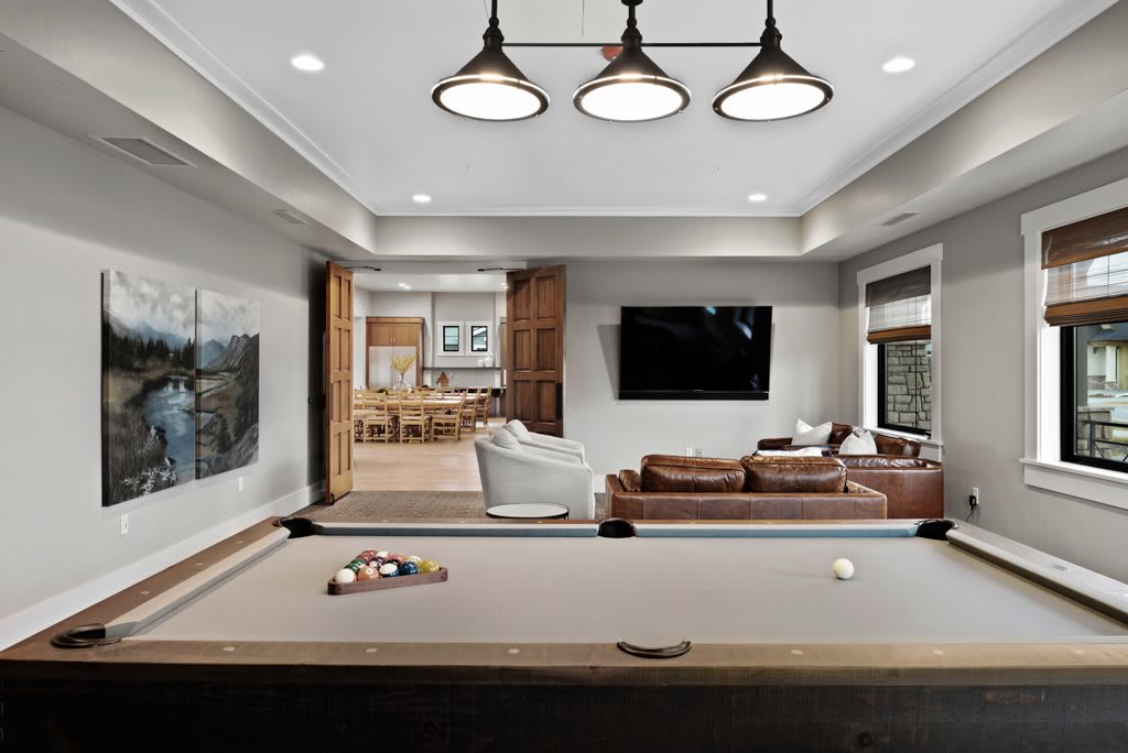 A modern living space featuring a pool table, seating area, and large television.