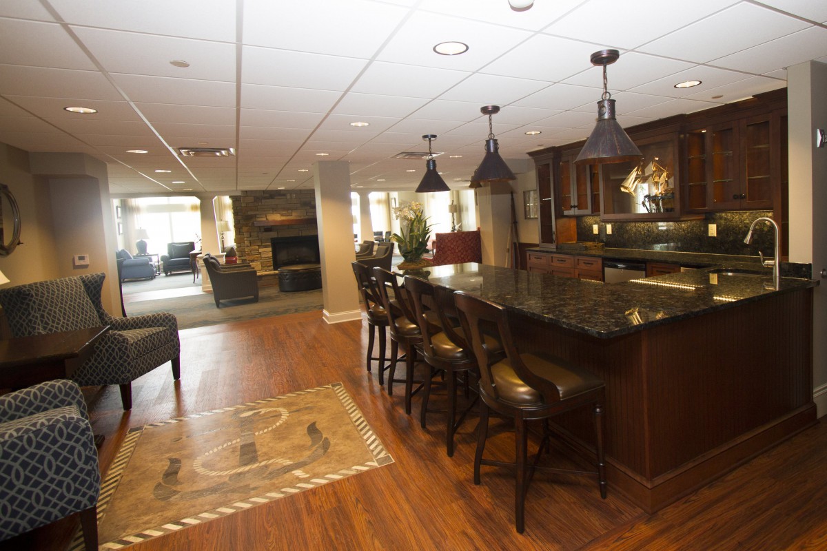 A modern kitchen with an open floor plan featuring a bar area with stools, pendant lighting, and hardwood floors.
