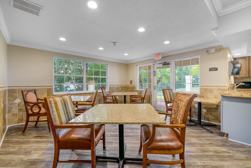 A bright and inviting dining area with several tables and chairs, featuring large windows that allow natural light to fill the space.