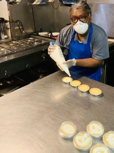 A chef is skillfully piping frosting onto cupcakes in a busy kitchen.