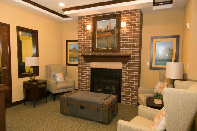 A cozy living room featuring a brick fireplace with seating and artwork.
