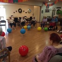 A group of seniors participating in an indoor exercise session using colorful balls.