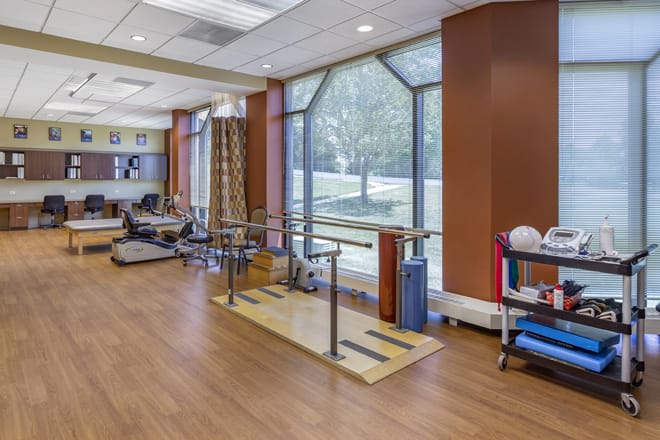 A physical therapy and rehabilitation room with exercise equipment, including parallel bars.