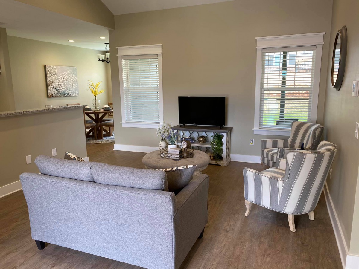 A cozy living room with a sofa, armchairs, and a television.