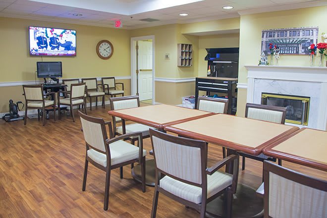 A meeting or common room with tables and chairs, equipped with a television and clock on the wall.