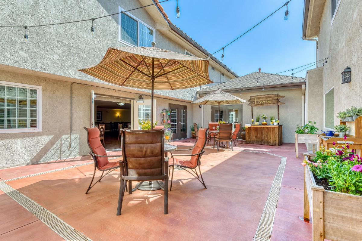 Spacious outdoor patio with seating and umbrellas under string lights.