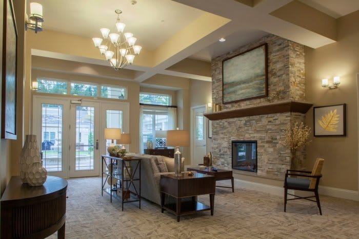 A cozy living room with a stone fireplace and elegant chandelier.