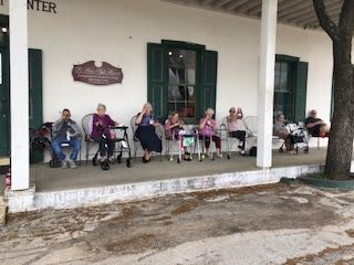 A group of seniors sitting on a porch, enjoying a peaceful moment together.