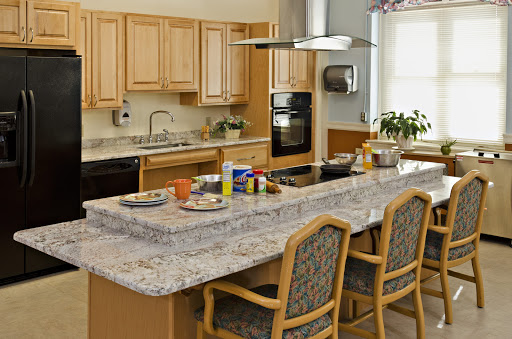 A spacious and modern kitchen featuring a granite countertop with bar stools and wooden cabinetry.