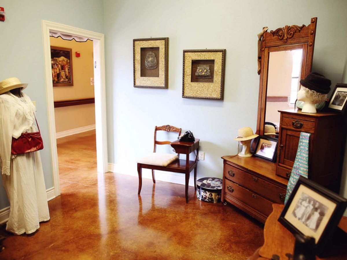 A cozy hallway featuring a wooden chair, dresser with mirror, and framed artwork on the walls.