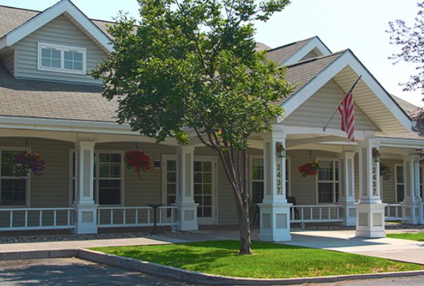 A charming suburban house with a spacious porch and an American flag.