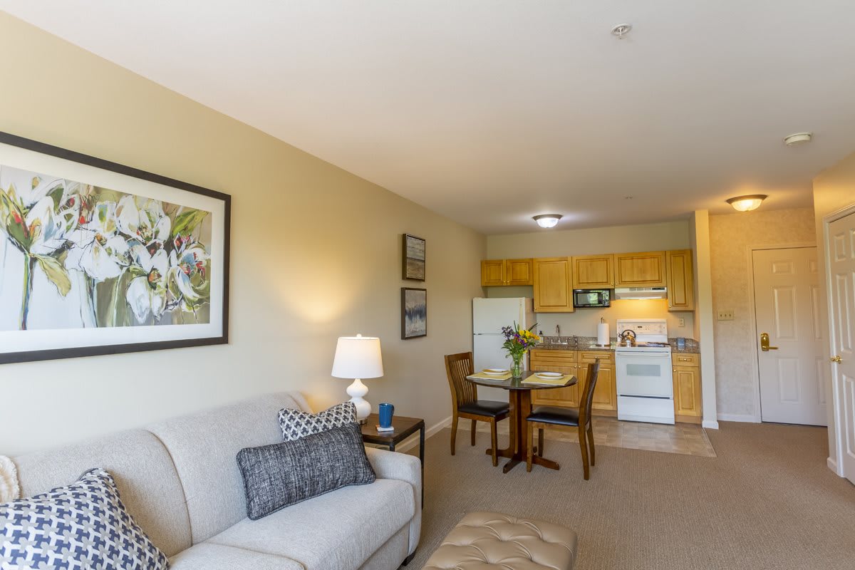 A cozy open-concept living room and kitchen area with a sofa, dining table, and modern appliances.