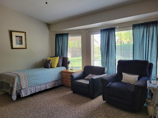 A cozy living space featuring a bed, two comfortable chairs, and large windows that let in plenty of natural light.