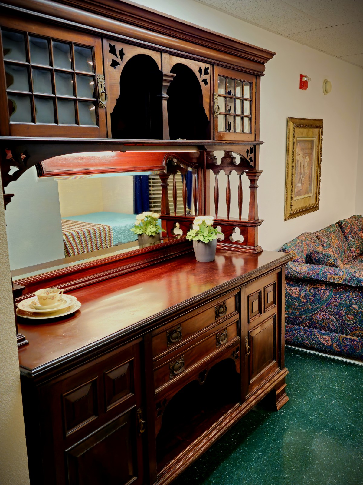 An intricately designed wooden cabinet adorned with plants, situated in a cozy living room setting.