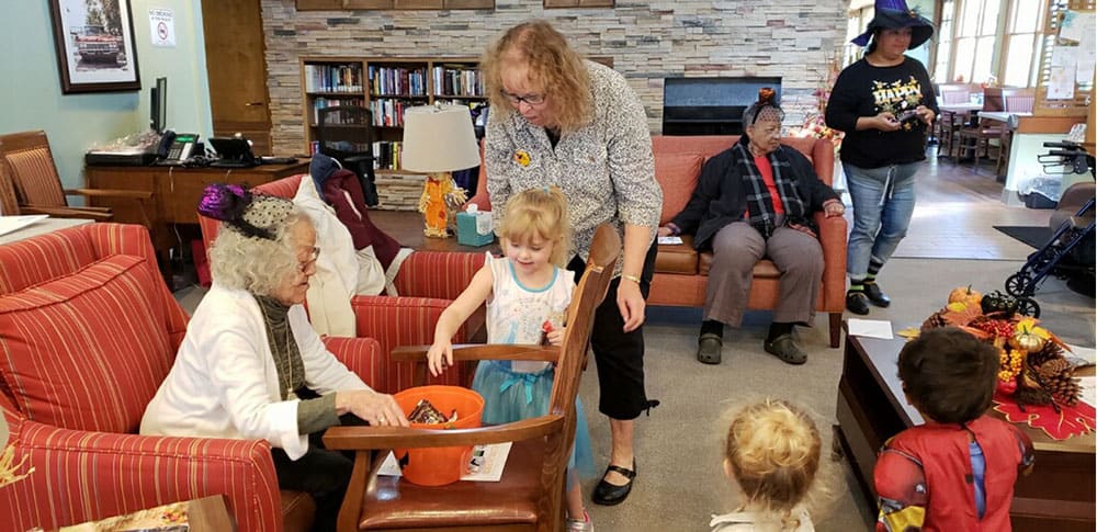 A child collecting candy from an elderly person during a community gathering in a library.